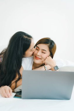 Igbtq, Igbt konsepti, homoseksüellik, iki Asyalı kadının birlikte mutlu poz verip birbirlerini severken yatakta bilgisayar bilgisayarı oynaması..