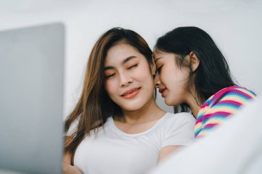 Igbtq, Igbt konsepti, homoseksüellik, iki Asyalı kadının birlikte mutlu poz vermeleri ve yatakta tablet oynarken birbirlerini sevmeleri..