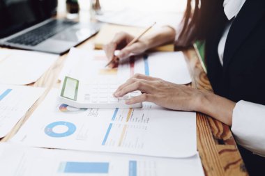 Finansal, Planlama, Pazarlama ve Muhasebe, Asyalı kadın ekonomist, diğer şirketlerle rekabet etmek için ortaklarla yatırım belgeleri hesaplamak için hesap makinesi kullanıyor..