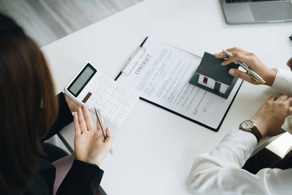 Гарантия, ипотека, договор, договор, подписанный договор, агент по недвижимости или банковский служащий, держащий калькулятор, подает заявку с клиентом на покупку дома до подписания сделки.