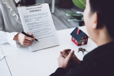Teminat, ipotek, sözleşme, sözleşme, imza, erkek müvekkil emlakçı veya banka memuruyla arazi kredisi imzalamak için anlaşma belgesine kalem tutuyor