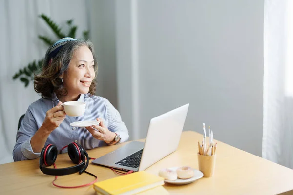 relax time, Portrait of an elderly woman listening to music happily to relax between computer sessions.