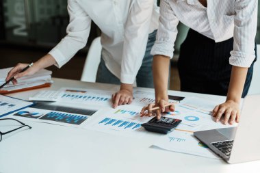 Finansal, Planlama, Pazarlama ve Muhasebe, Asyalı kadın ekonomist, diğer şirketlerle rekabet etmek için ortaklarla yatırım belgeleri hesaplamak için hesap makinesi kullanıyor..