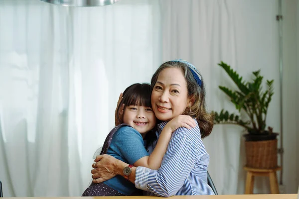 Asyalı portre, büyükanne ve torun boş zaman aktiviteleri yapıyor ve birbirlerine sevgilerini ve ilgilerini göstermek için sarılıyorlar..