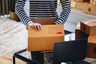 Çevrimiçi ticaret fikri, güzel bir kız müşteriden gelen siparişe göre teslimatı hazırlamak için ürünleri paket teslimat kutusuna koyuyor.