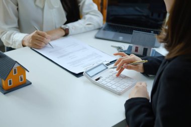 Teminat, mortgage, sözleşme, sözleşme, imzalı, emlakçı veya banka memuru hesap makinesini işaret ederek, anlaşma imzalamadan önce bir ev satın almak için müşteriye teklif sunar..