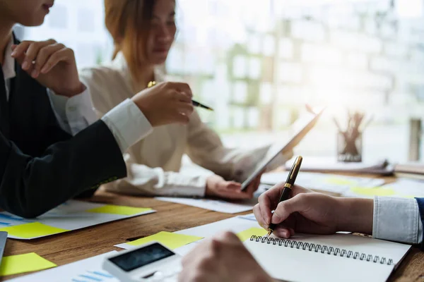 Erkek işadamı elinde kalem tutarak kadın meslektaşlarıyla toplantı, takım çalışması ve yatırım planlamasında pazarlama stratejisini özetliyor.