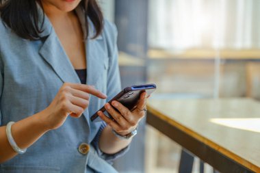 Asian women using smartphone mobile in capital planning to increase company profits.