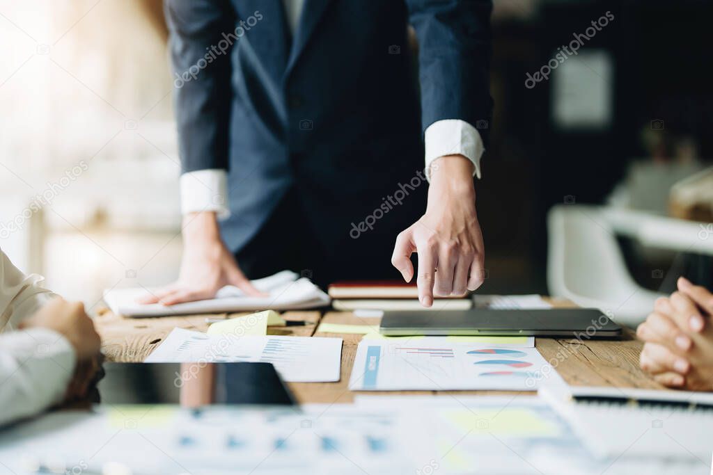 Male businessman pointing to documents summarizing marketing strategy with female colleagues in meeting, teamwork, investment planning.