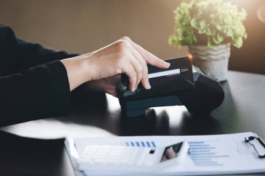 Safe technology concept from using credit card, employee is holding customers credit card to pay for service or payment via electronic card swipe machine