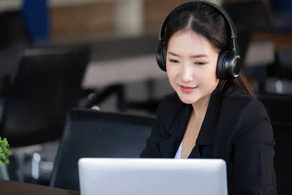 Concept of taking a break from work, an accountant or a female company employee or a business owner is using headphones to listen to music to relieve stress and fatigue from work