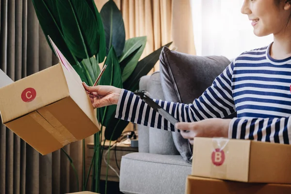 Business idea to sell products online, beautiful girls at home are holding parcel boxes. Customers come to check the shipping address before packing the products into the parcel box