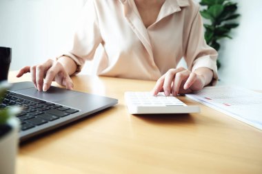 İş kadını, hesap makinesini kullanarak yıllık bilançoları gözden geçiriyor. Bütçe hesaplamak için belge ve dizüstü bilgisayar kullanıyor. Yatırım kavramından önce denetim ve denetim bütünlüğü.