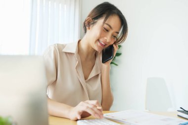 Yeni normal, bilgisayar ve akıllı telefon kullanan bir iş kadını bir şirket için çalışmak için evdeki masandaki internet üzerinden
