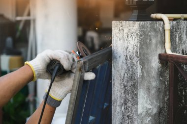 The contractor is using an electric grinder to decorate the steel welding point