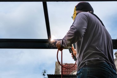 The welder is welding the steel structure to add to the house