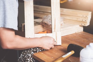 Bir marangoz parçaları birleştirmek için kalasları ölçer ve müşteri için ahşap bir masa yapar..
