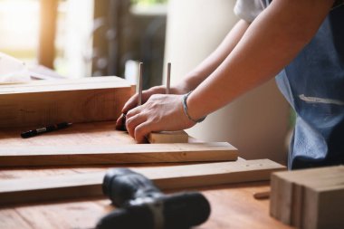 Bir marangoz parçaları birleştirmek için kalasları ölçer ve müşteri için ahşap bir masa yapar..