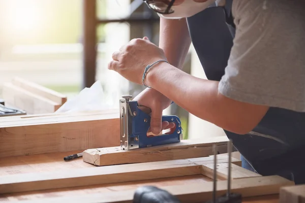 Entrepreneur Woodwork holding a Tacker to assemble the wood pieces as the customer ordered.