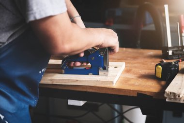 Girişimci Woodwork, müşterinin emrettiği gibi tahta parçaları birleştirmek için bir raptiye tutuyor..