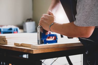 Girişimci Woodwork, müşterinin emrettiği gibi tahta parçaları birleştirmek için bir raptiye tutuyor..