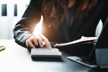 İş kadını, hesap makinesini kullanarak yıllık bilançoları gözden geçiriyor. Bütçe hesaplamak için belge ve dizüstü bilgisayar kullanıyor. Yatırım kavramından önce denetim ve denetim bütünlüğü.