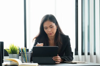 İş kadını, yıllık bilançosunu incelemek için tablet kullanıyor. Bütçeyi hesaplamak için belge kullanıyor. Yatırım kavramından önce denetim ve denetim bütünlüğü