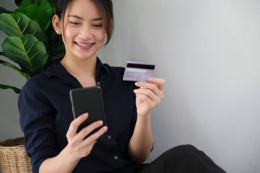 Online payment, Young Womens hands holding credit card and using smartphone for online shopping at home.