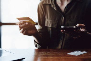 İnternetten alışveriş için kredi kartı ve telefon kullanan Asyalı genç bir kadının portresi..