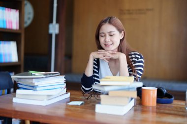 Genç Asyalı bir kadının portresi. Gülümseyen bir yüzü var. Sabahları kütüphanede oturmuş kitap okuyor..