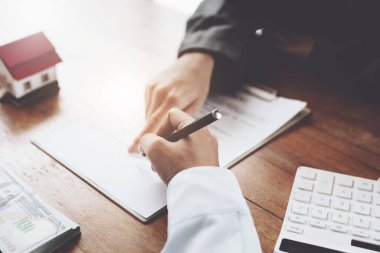 Bir çift, emlakçıyla evrakları imzalamadan önce ev satın alma sözleşmesi okuyor..