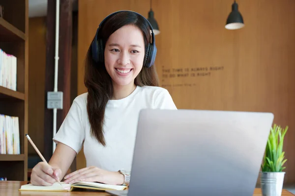 아시아의 컴퓨터를 사용하고 헤드폰을 노트북을 사용하여 도서관에 책상에서 비디오 회의를 — 스톡 사진