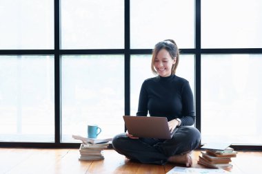 İnternette çalışmak ve video konferansı sırasında kahve içmek için bilgisayar kullanan Asyalı bir kadının portresi.