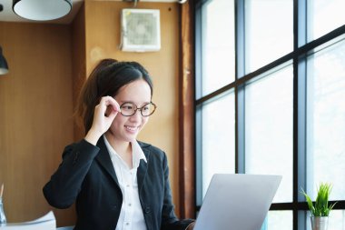 Bilgisayarla ve finansal bilgilerle gülümseyen Asyalı genç bir kadının portresi.
