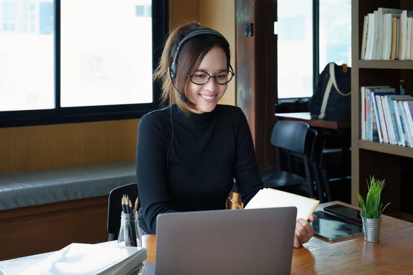 아시아의 컴퓨터 헤드폰을 안경을 착용하고 나무로 책상에서 비디오 회의를 온라인으로 — 스톡 사진