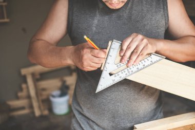 Bir marangoz parçaları birleştirmek için plakaları ölçer. Ve müşteriler için ahşap bir masa yap.