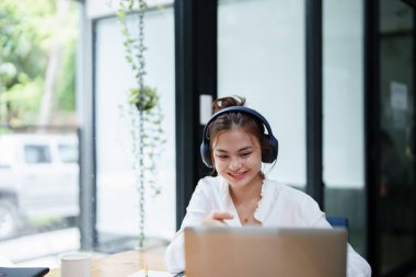 Video konferans sırasında bilgisayar ve kulaklık kullanan güzel bir kadının portresi.