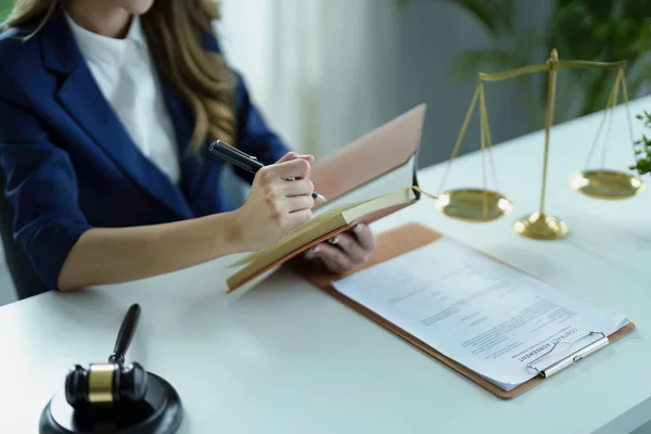 Genç bir Asyalı avukatın portresi bir müvekkil için masa başında defter ve evrak kullanarak dava üzerinde çalışıyor..