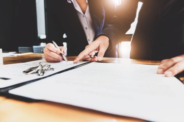 Emlakçı, müşteriyle sözleşme imzalaması için kalem ve belge anlaşması veriyor. Kavram anlaşması