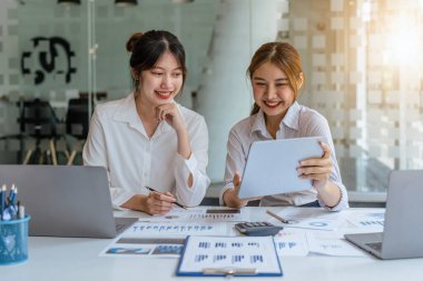 Müzakere, Analiz, Tartışma: Asyalı bir kadın ekonomist ve pazarlamacının tablet bilgisayarı kullanarak şirketin risk ve zararlarını önlemek için yatırım ve finans planlaması.
