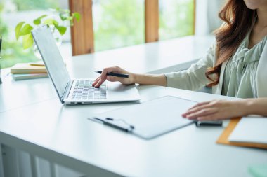 Asyalı bir banka çalışanının portresi. Finansal tabloları yönetmek için bilgisayar ve belgeler kullanıyor..