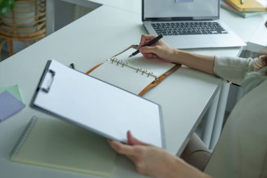 Finansal tabloları kapatmak için not defterleri, bütçe belgeleri ve bilgisayarlar kullanan Asyalı bir banka çalışanının portresi.