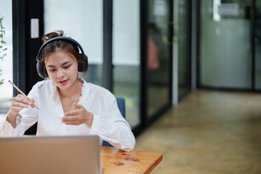 Video konferans sırasında bilgisayar ve kulaklık kullanan güzel bir kadının portresi.