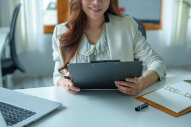 Asyalı bir banka çalışanının portresi. Finansal tabloları yönetmek için bilgisayar ve belgeler kullanıyor..