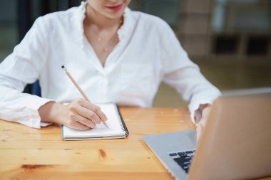 Bir video konferansı sırasında bilgisayar ve defter kullanan bir kadın, e-öğrenim kavramları
