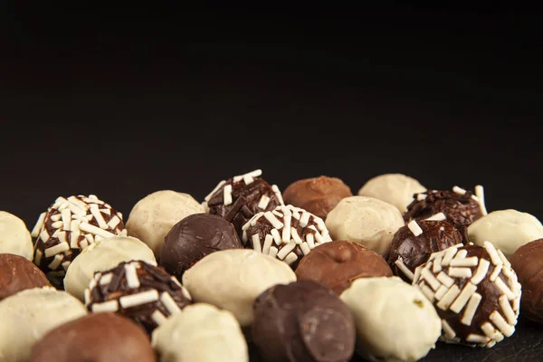 Handmade chocolate bonbon, luxury handmade chocolate bonbon with copy space black or dark background. Assorted pralines with selective focus on black background, close up view.