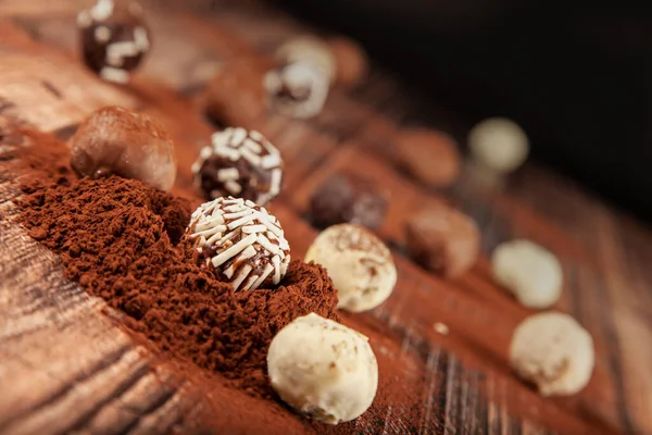 Chocolate pralines, selective focus of chocolate pralines on wooden background with cocoa powder. chocolate concept idea background photo.