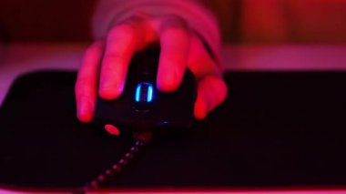 Oyuncu fare, oyun faresinin eline yaklaş. E-sporcu oyun oynayıp fareye tıklayın. Karanlık bir odada oyun oynayan siber sporcu, oyuncuların eline yansıyan havalı rgb neon ışıkları.