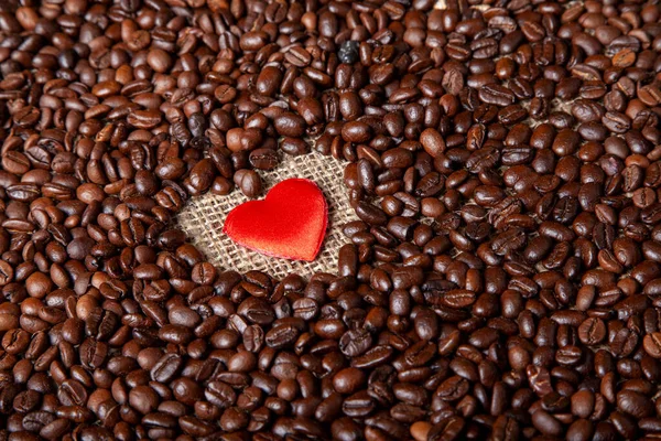 Love of coffee, dark roasted coffee beans and a red hearth love of coffee concept idea photo.