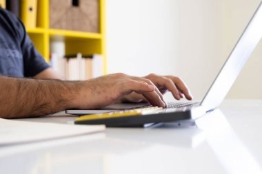 Dizüstü bilgisayar ve hesap makinesi kullanarak bilgisayarın ve hesap makinesinin görüntüsünü kapat. İşadamı bir proje üzerinde çalışıyor, klavyeyle not defteri yazıyor. Finansal belgeler üzerinde çalışıyorum, not alıyorum.. 